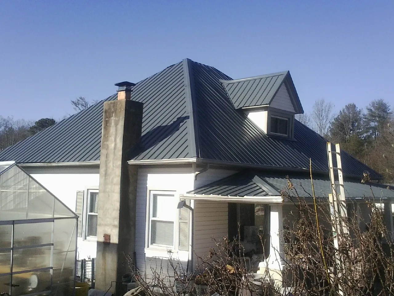 Dark blue standing seam metal roof on a white farmhouse with dormer — Slate & Tile Roof Repair by Roofing Brothers in Parrottsville