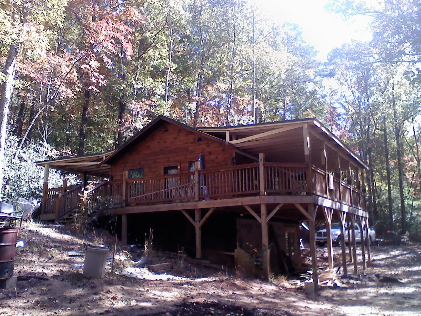 Log cabin with a wraparound porch and metal roof in the fall in Parrottsville