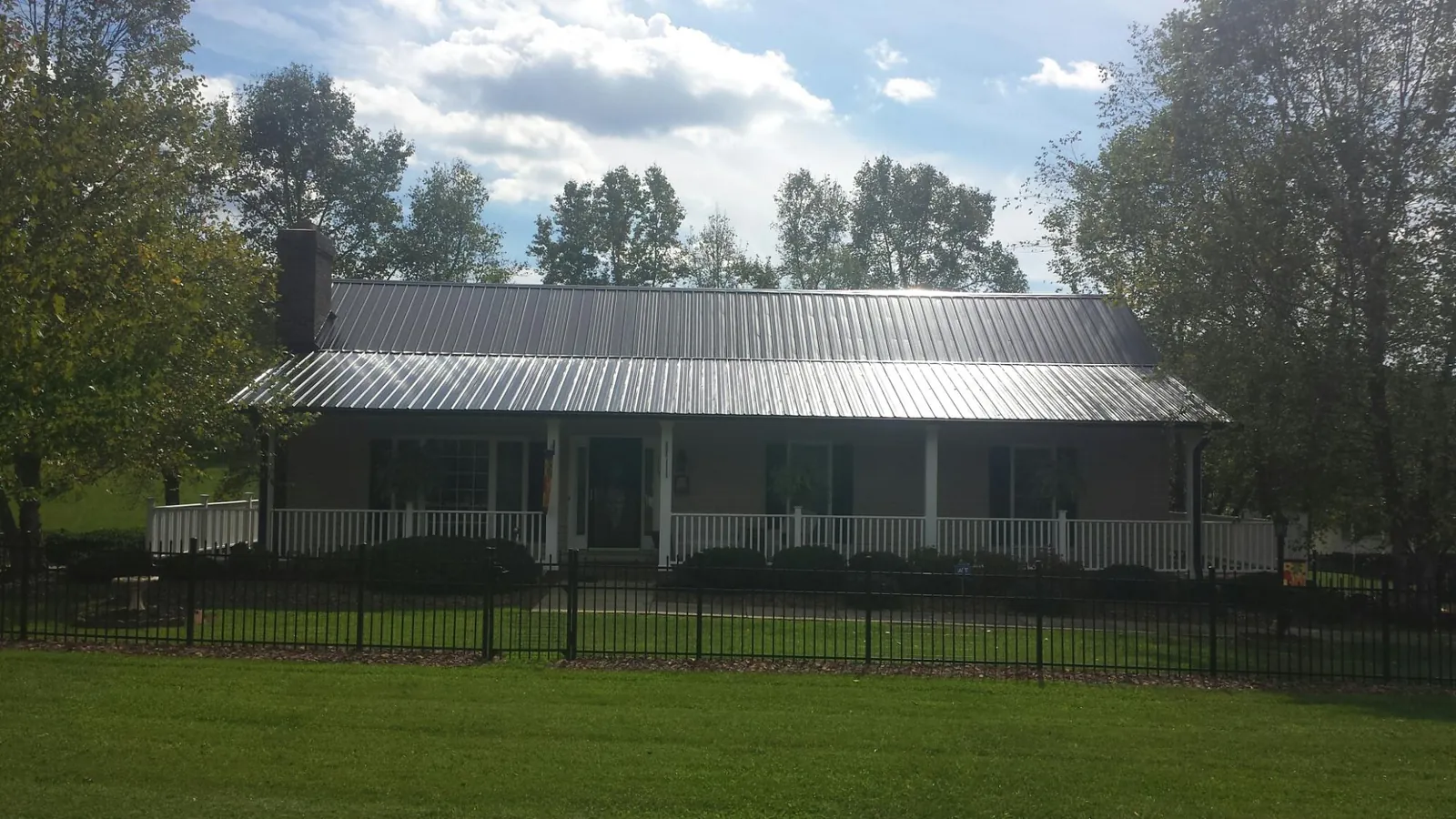 Gray metal roof on a brick ranch with a full width front porch — Gutter Guard Installation work by our crew in Parrottsville
