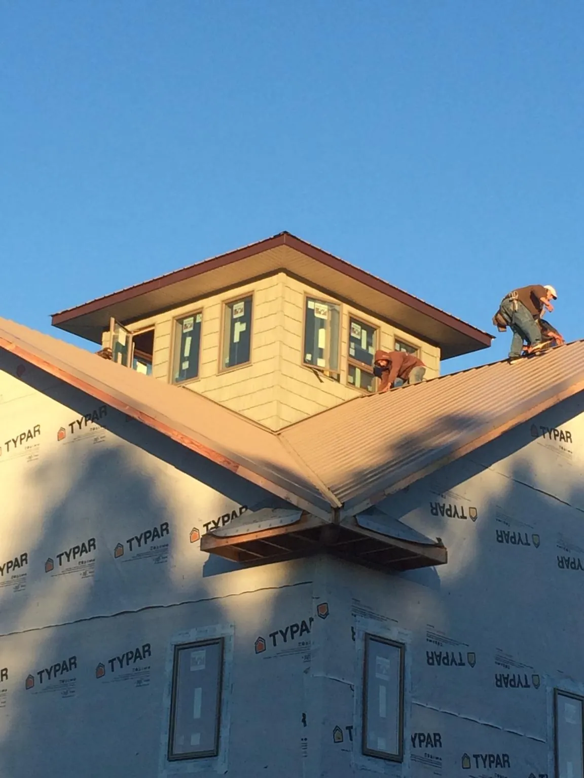 Roofers working around a rooftop cupola on a new metal roof at sunset — Roof Waterproofing in Parrottsville by Roofing Brothers